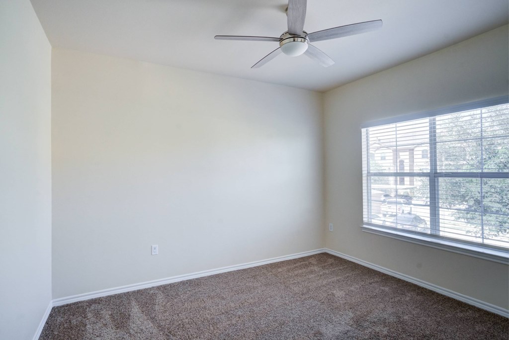 A room with a ceiling fan and a window with blinds.