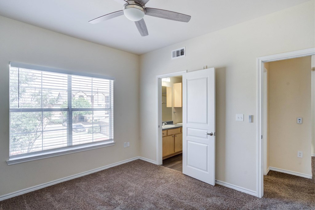 A room with a ceiling fan and a window with blinds.