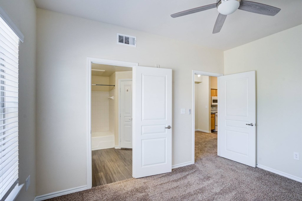 A room with a ceiling fan and three doors.