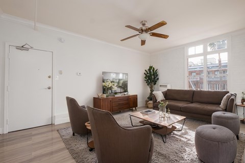 A living room with brown furniture and a ceiling fan.