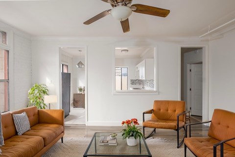 A living room with a brown sofa, two chairs, and a glass coffee table.