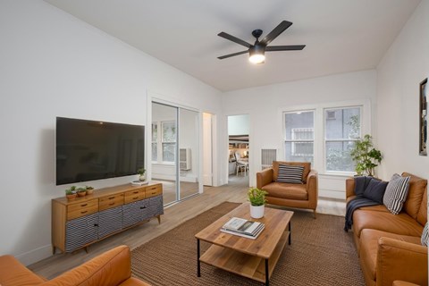A living room with a brown sofa, a wooden coffee table, and a flat-screen TV.
