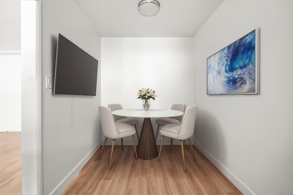 A modern dining room with a table set for two and a painting on the wall.