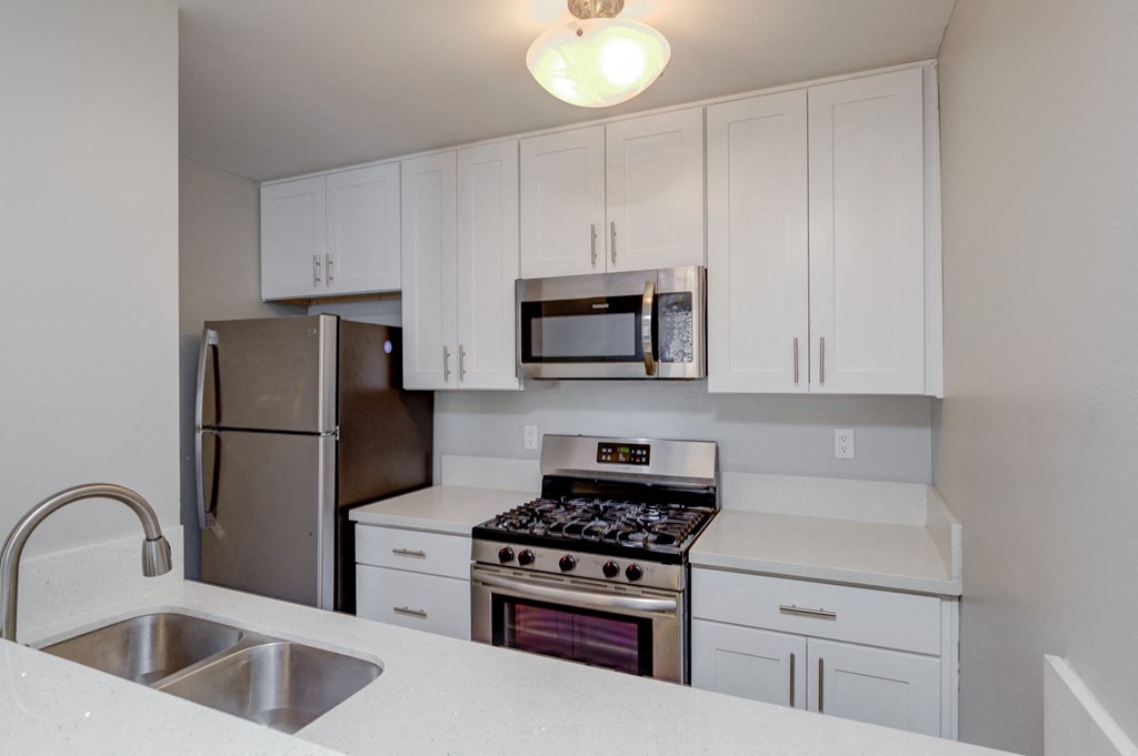 a kitchen with white cabinets and stainless steel appliances
