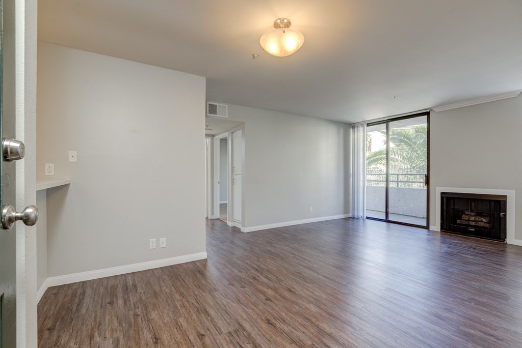 an empty living room with wood flooring and a fireplace