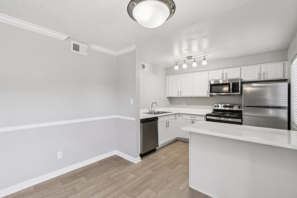A kitchen with white cabinets and a stainless steel refrigerator.