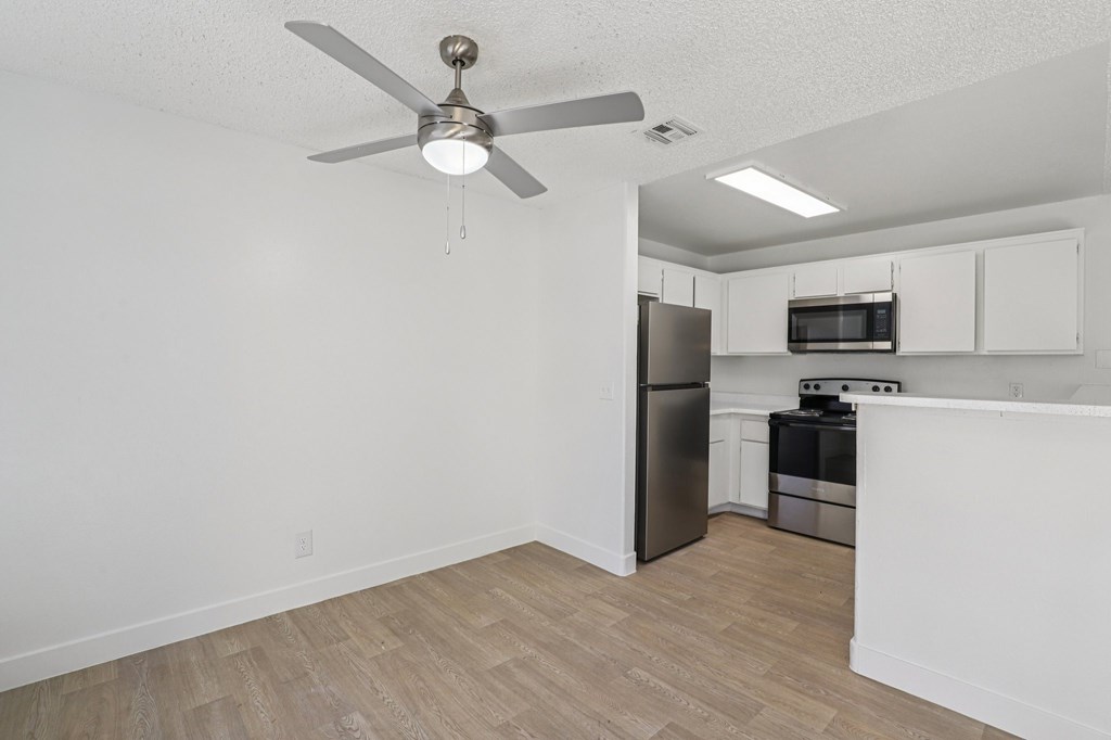 A kitchen with a refrigerator, microwave, and oven.