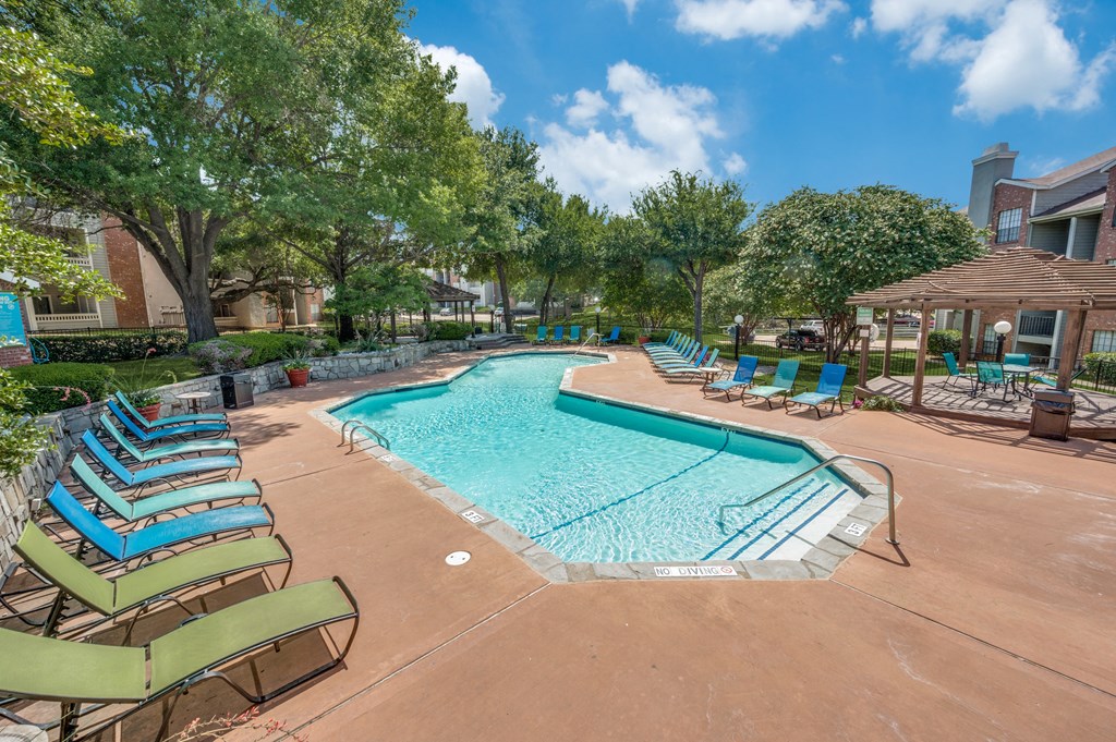 a resort style swimming pool with lounge chairs and umbrellas