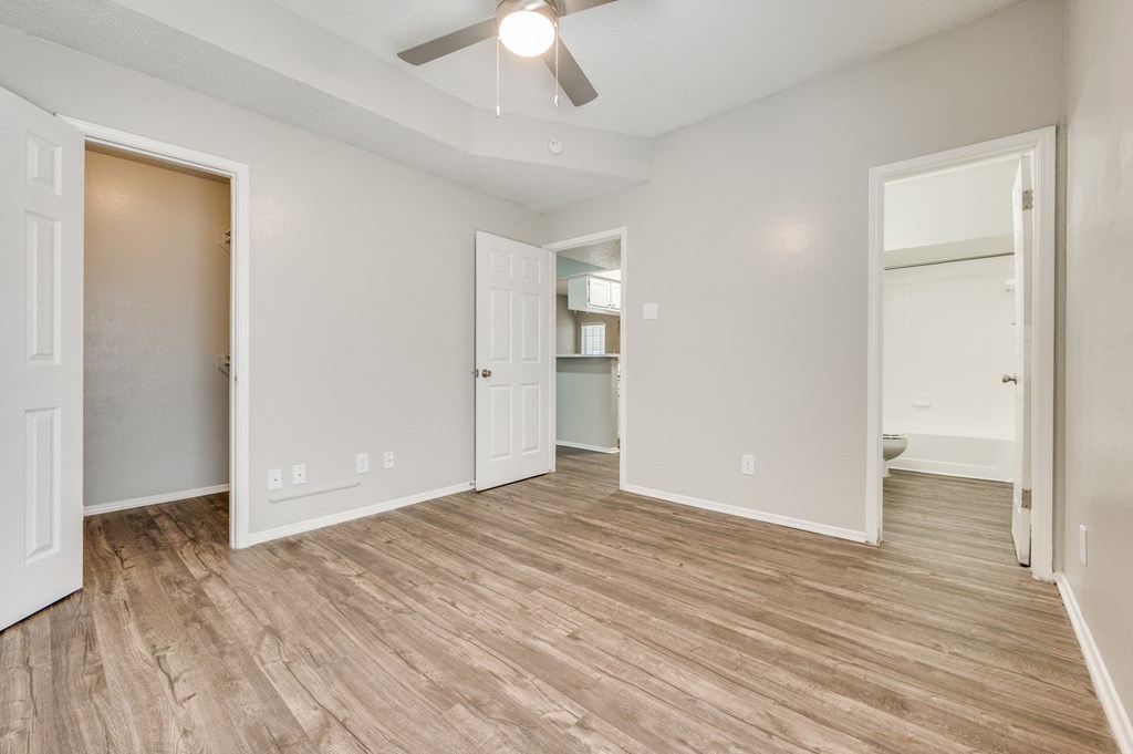 an empty living room with a wood floor and a ceiling fan
