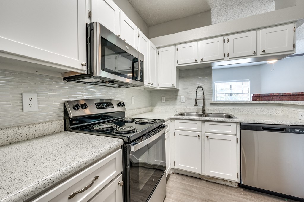 an empty kitchen with white cabinets and a stove and microwave
