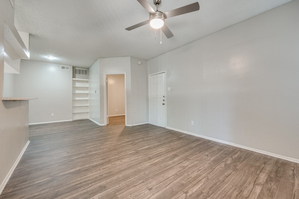 an empty living room with wood flooring and a ceiling fan