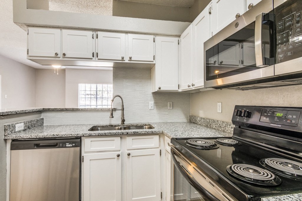 a kitchen with white cabinets and black appliances at Foxborough Apartments, Irving, TX, 75061