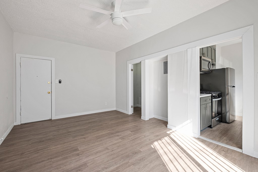 A room with a ceiling fan and a kitchen area in the background at Hillstone Flats Apartments, Los Angeles, CA