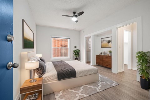 A bedroom with a bed, nightstand, and a plant.