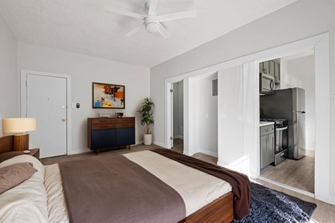 A bedroom with a bed, dresser, and a ceiling fan.