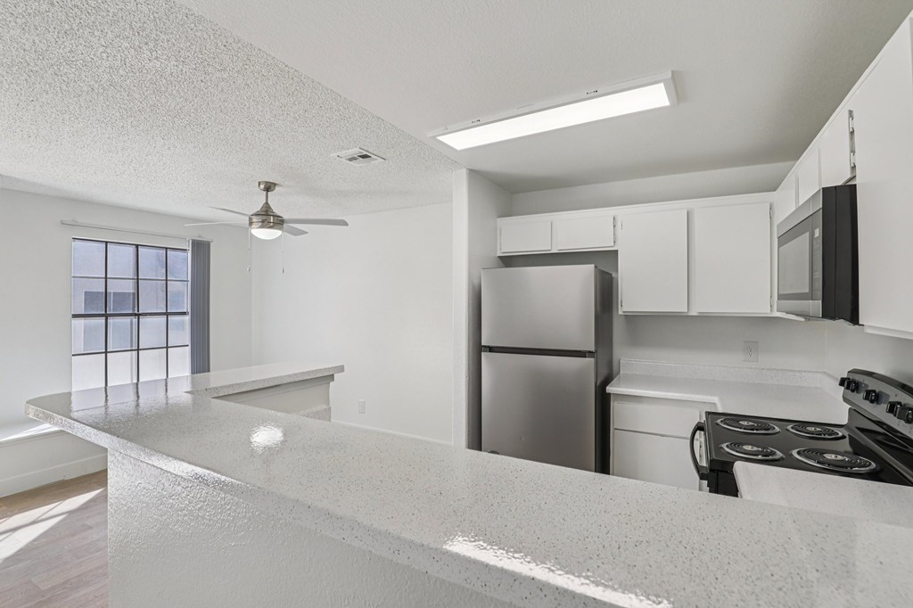 A kitchen with a refrigerator, stove, and microwave.
