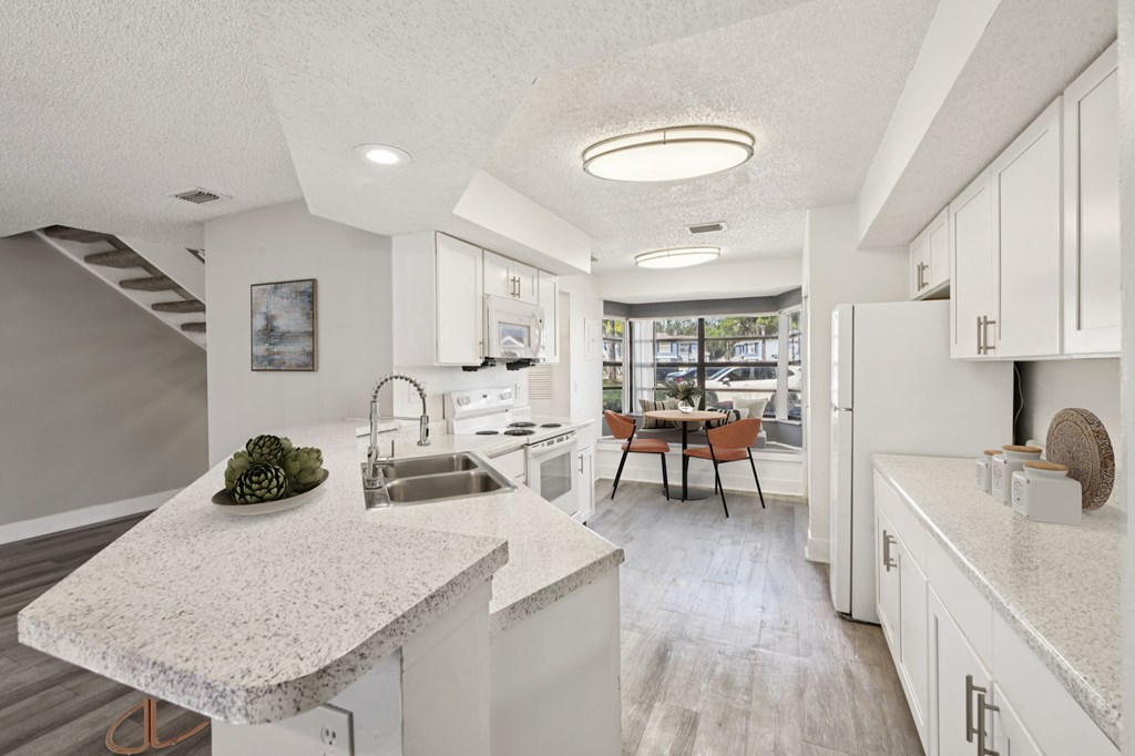 A modern kitchen with a marble countertop and a dining table with chairs.