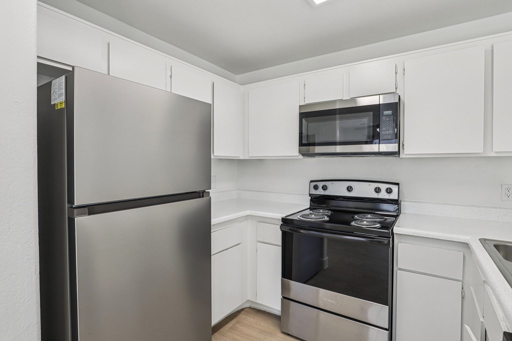 A kitchen with a stainless steel refrigerator, microwave, and oven.