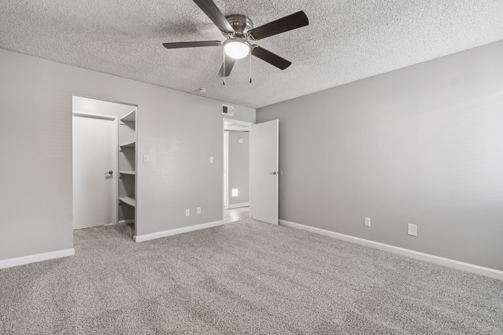 A room with a ceiling fan and carpeted floor.