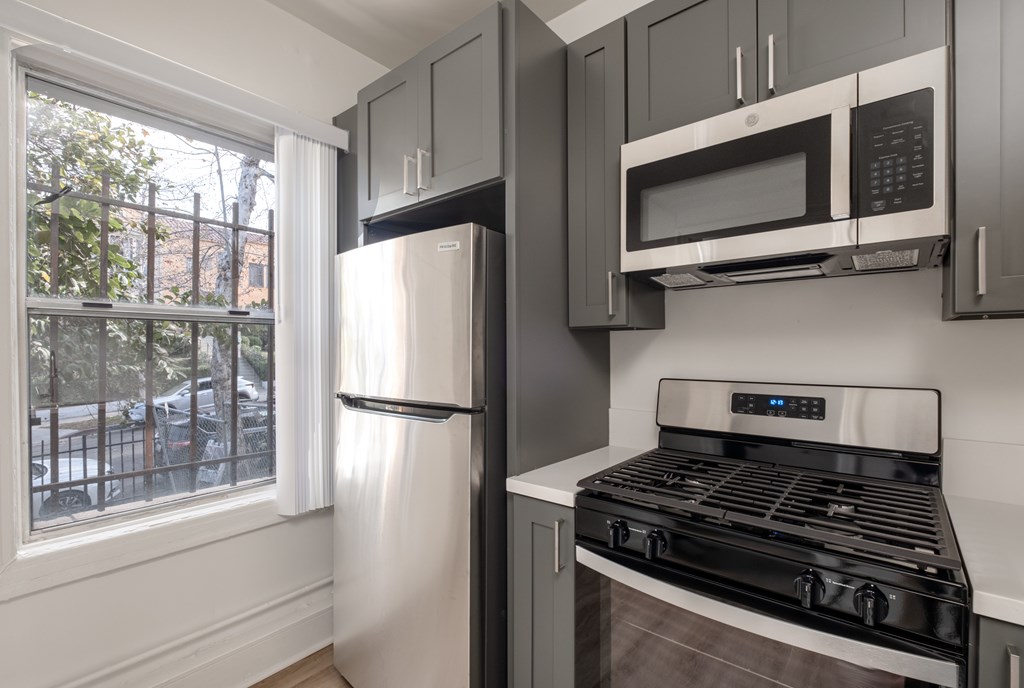A kitchen with a stove, refrigerator, and microwave at Kenmore Park Apartments, Los Angeles, CA