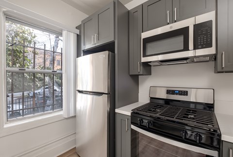 A kitchen with a stove, refrigerator, and microwave.