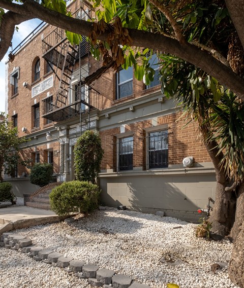 A tree is in front of a building with a sign at Kenmore Park Apartments, Los Angeles, 90004