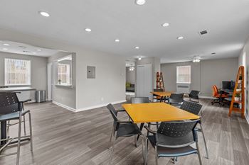 a community room with tables and chairs and a kitchen