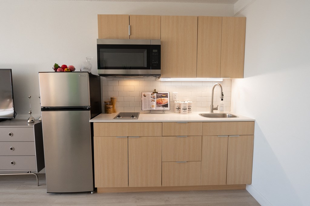 a small kitchen with a sink and a refrigerator at Vision on Lombard, Baltimore, 21201