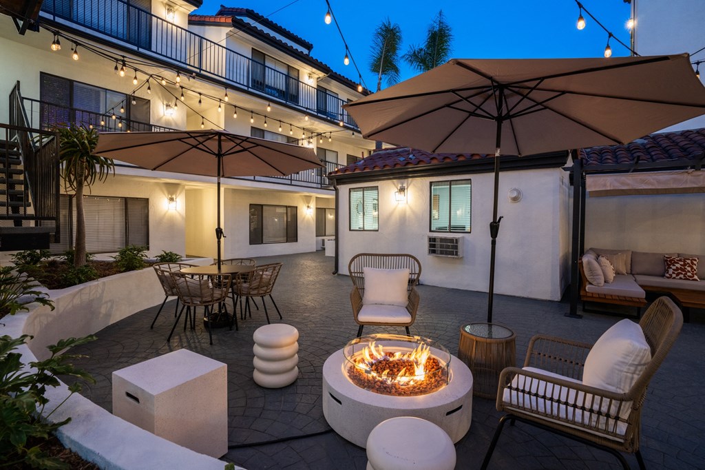 a patio with a fire pit and chairs and umbrellas