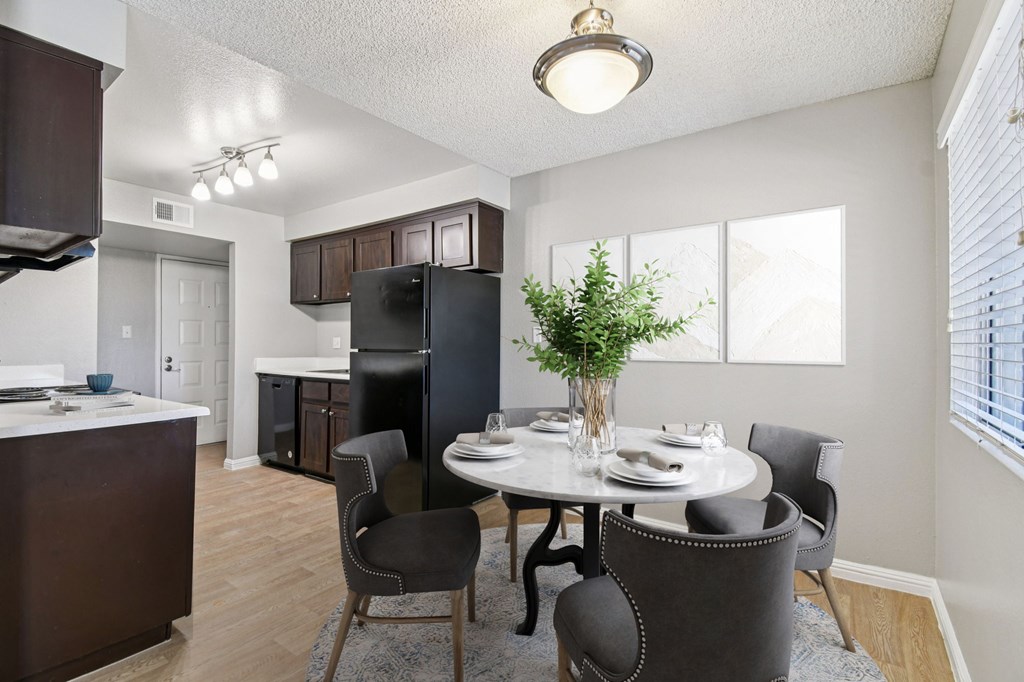 A dining room with a table set for two and a potted plant on the table.