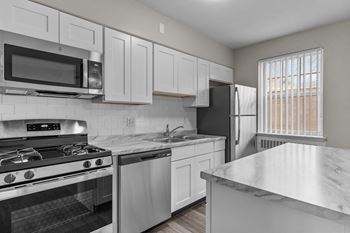 an all white kitchen with stainless steel appliances and marble counter tops