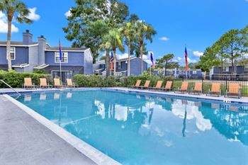 A swimming pool in front of a house with palm trees.