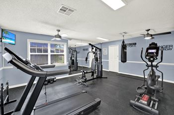 A gym with a treadmill, weights, and a television.