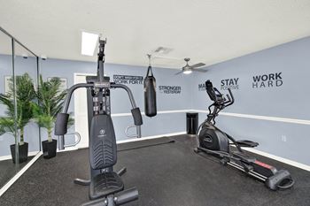 A gym room with a treadmill, a stationary bike, a rowing machine, and a wall with the words "Stay Positive" and "Work Hard".