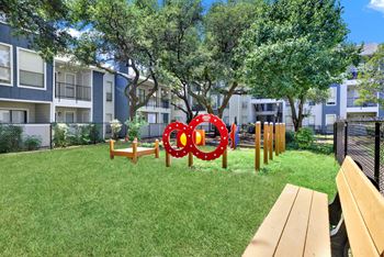 A playground with a red and white circular structure in the middle of a grassy area.