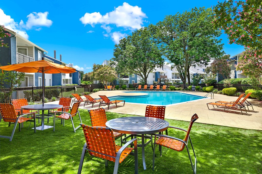 A poolside table and chairs are set up on a sunny day. at Seacrest Apartments, Garland, 75044