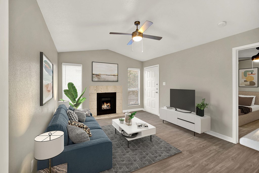 A living room with a blue couch, a fireplace, and a television. at Seacrest Apartments, Garland, Texas