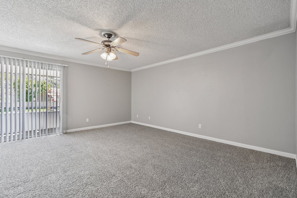 A room with a ceiling fan and carpeted floor.