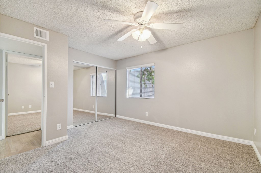 A spacious room with a ceiling fan and carpeted floor.