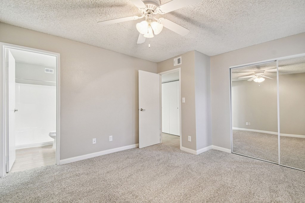 A spacious room with a ceiling fan and a large mirror on the wall.
