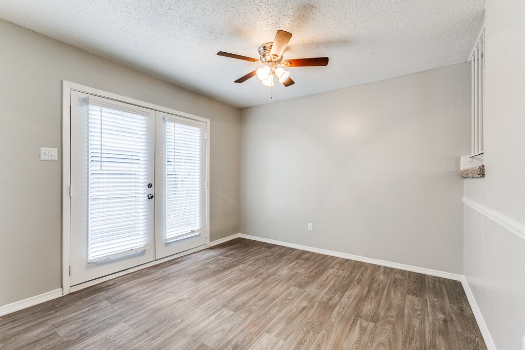 an empty living room with a ceiling fan and a door at Falls on Clearwood Apartments, Richardson, TX, Texas