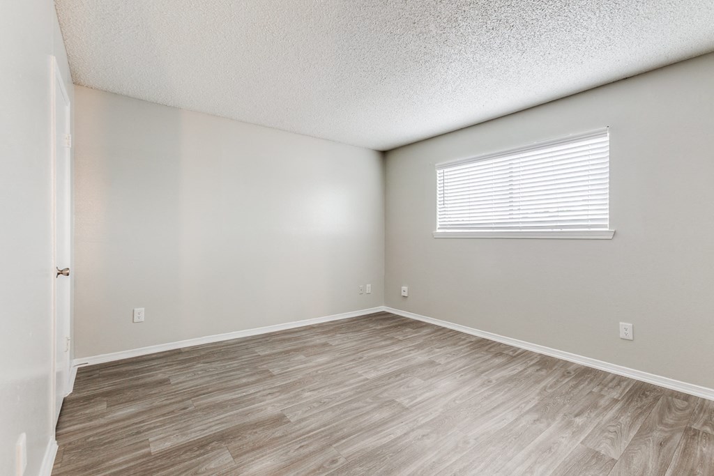 the spacious living room with wood flooring and a window at Falls on Clearwood Apartments, Richardson, TX, Texas