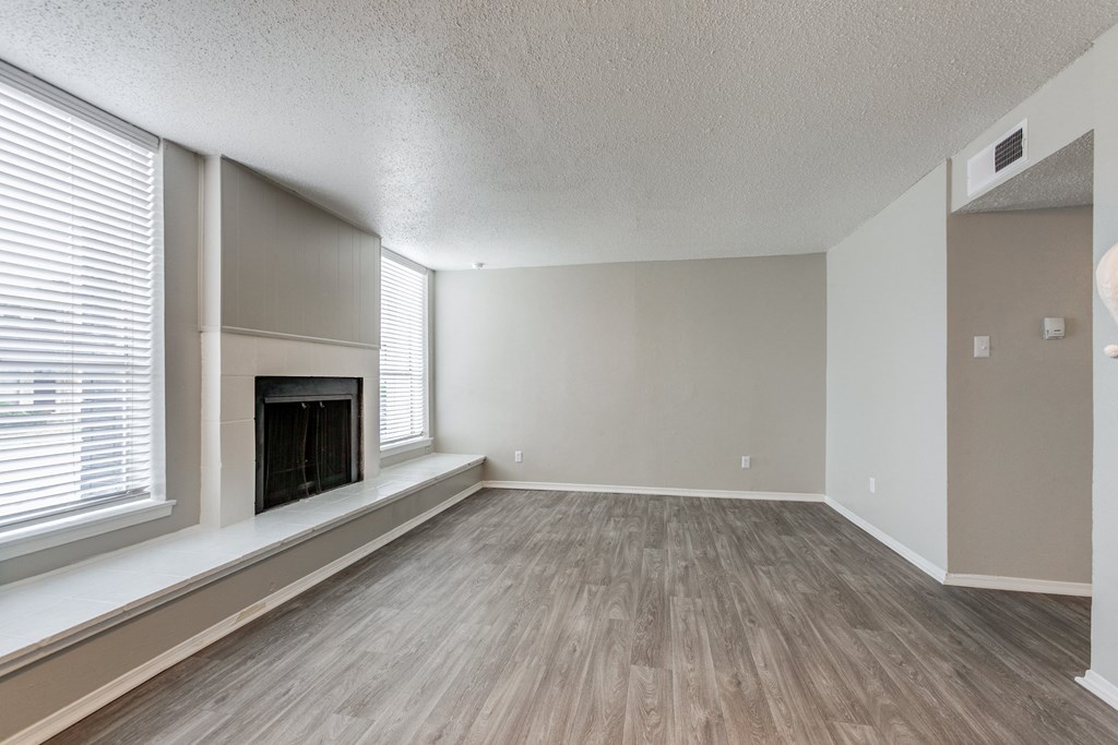 an empty living room with a fireplace and a large window at Falls on Clearwood Apartments, Richardson, TX, Texas