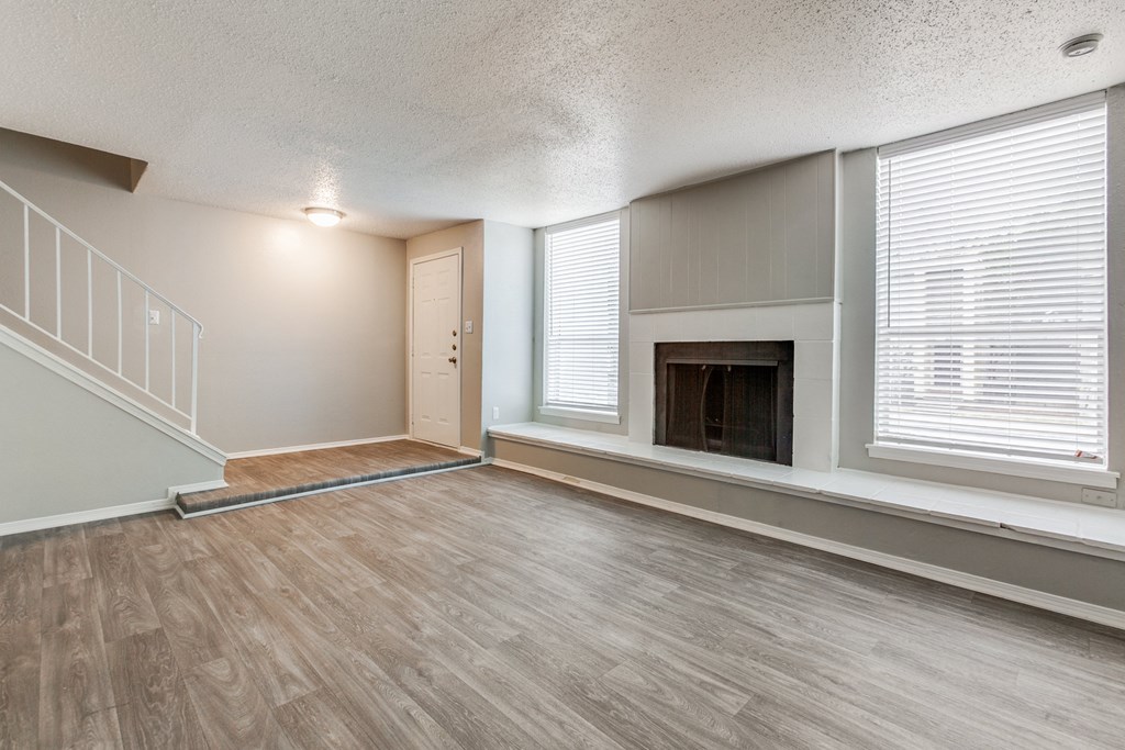 an empty living room with a fireplace and a staircase at Falls on Clearwood Apartments, Richardson, TX, Texas