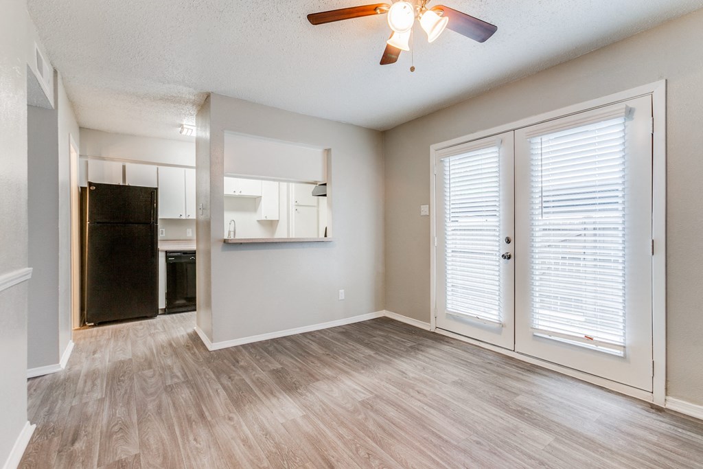 an empty living room with a kitchen and a ceiling fan at Falls on Clearwood Apartments, Richardson, TX, Texas
