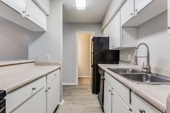 an empty kitchen with white cabinets and a sink