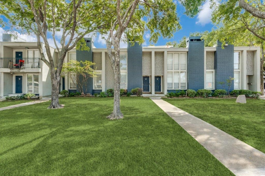 an apartment building with grass and trees in front of it at Falls on Clearwood Apartments, Richardson, TX, Texas