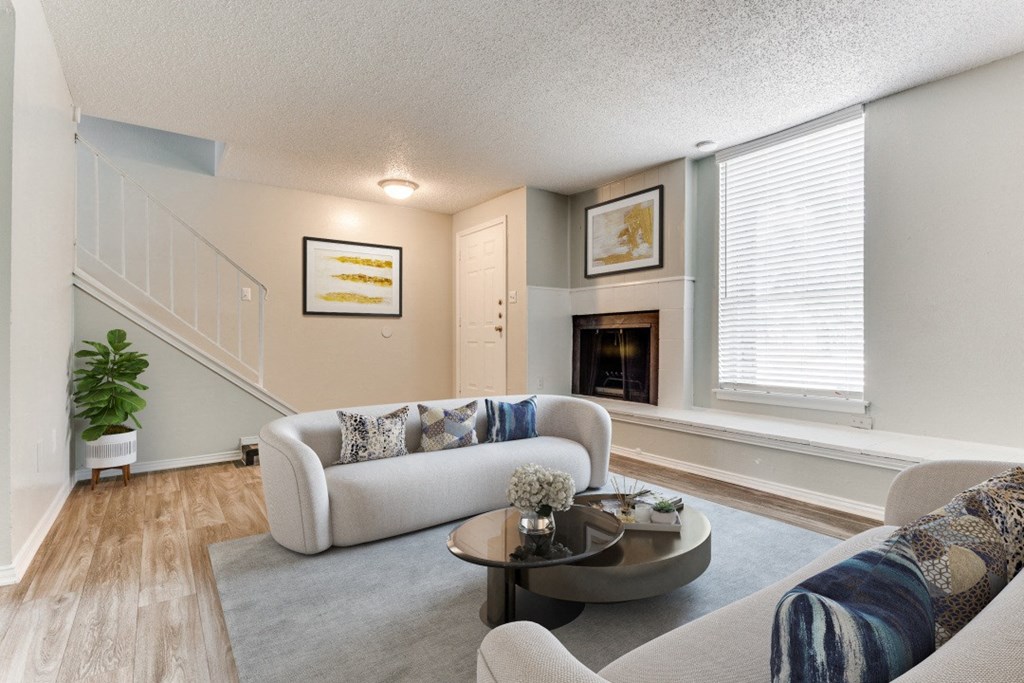 a living room with a couch and a table in front of a fireplace at Falls on Clearwood Apartments, Richardson, TX, Texas