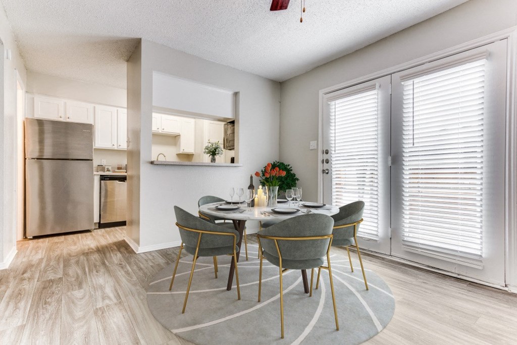 a dining room with a table and chairs and a kitchen with stainless steel appliances at Falls on Clearwood Apartments, Richardson, TX, Texas