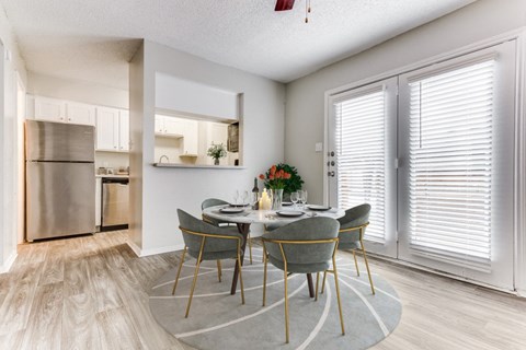 a dining room with a table and chairs and a kitchen with stainless steel appliances at Falls on Clearwood Apartments, Richardson, TX, Texas
